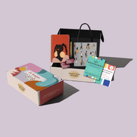 An opened box with items popping out. Inside is a red notebook with black woman's face with braids whos is wearing large earrings that say "Protect Your Energy," the books Set Boundaries, Find Peace and the Set Boundaries Workbook by Nedra Tawwab Glover, a shiny gold pen, Decompress cards, and a tote bag with illustrations of people all over